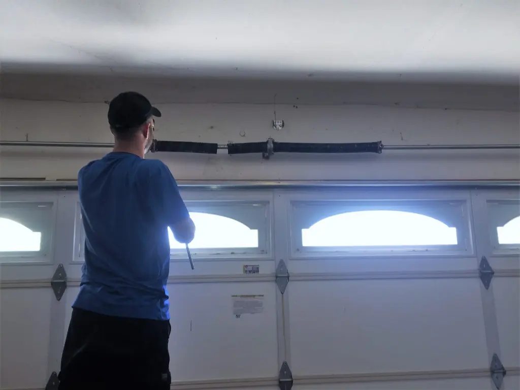 Garage door technician adjusting the hardware on a residential door in Lancaster, CA