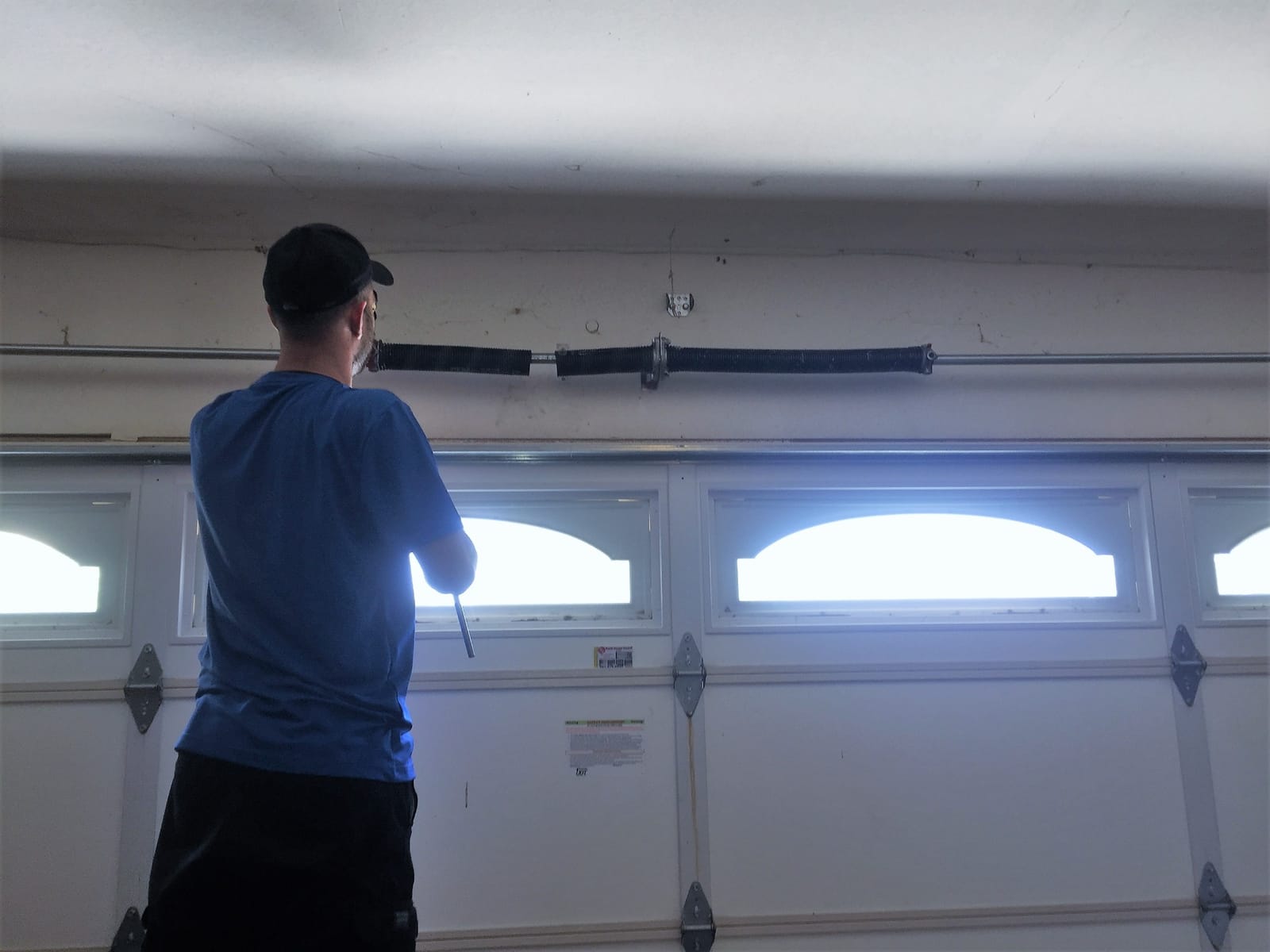 Garage door technician adjusting the hardware on a residential door in Lancaster, CA